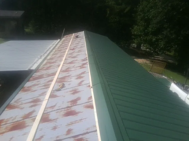Old rusted panels beside newly installed green metal roofing — Wind Damage Roof Repair by Roofing Brothers in Maxatawny