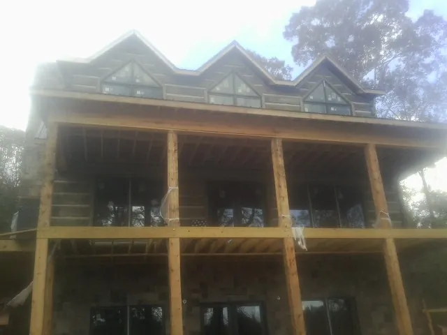 Dormers and porch framing on a large log home under construction — Roof Coating work by our crew in Maxatawny