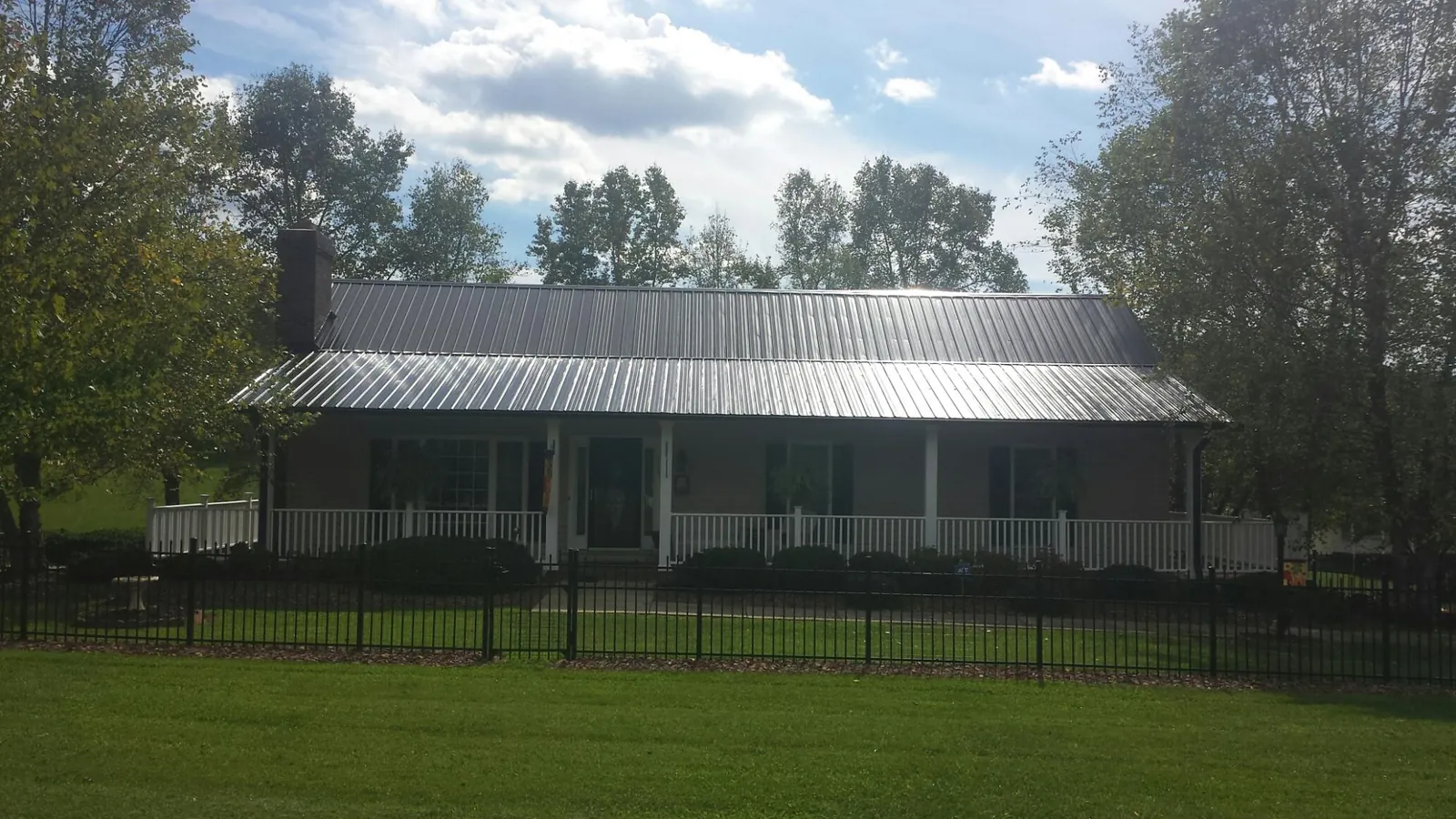 Gray metal roof on a brick ranch with a full width front porch — Gutter Guard Installation work by our crew in Maxatawny