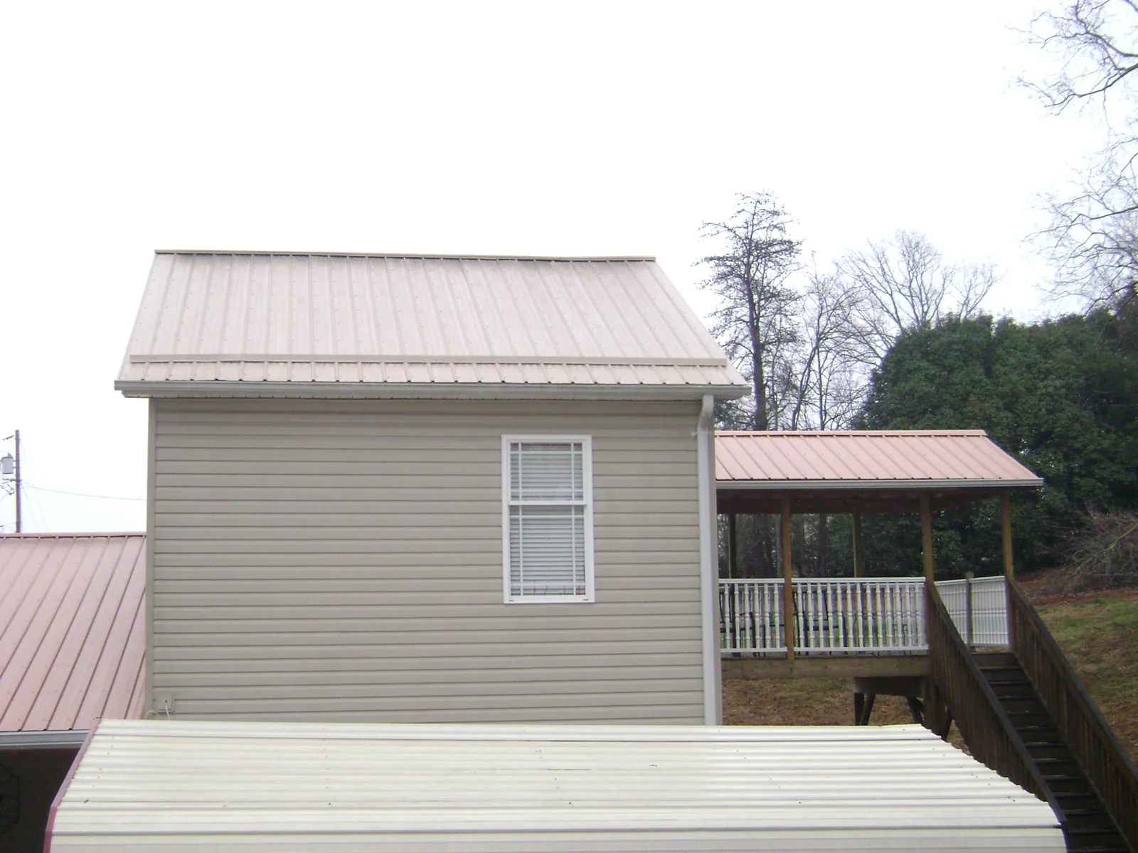 Tan metal roofs on a two story addition and attached porch, from a Roof Replacement job in Maxatawny