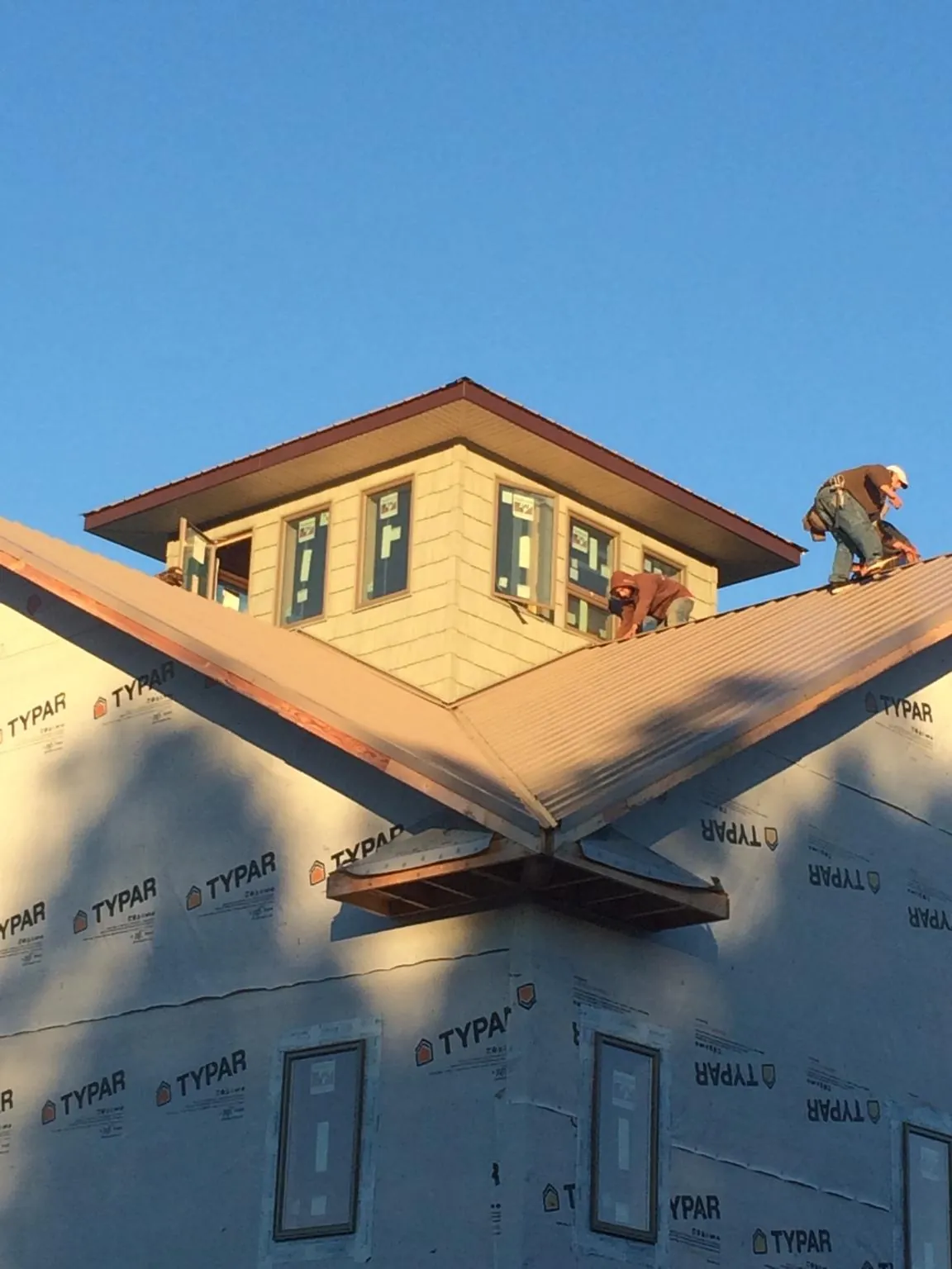Roofers working around a rooftop cupola on a new metal roof at sunset — Roof Waterproofing in Maxatawny by Roofing Brothers